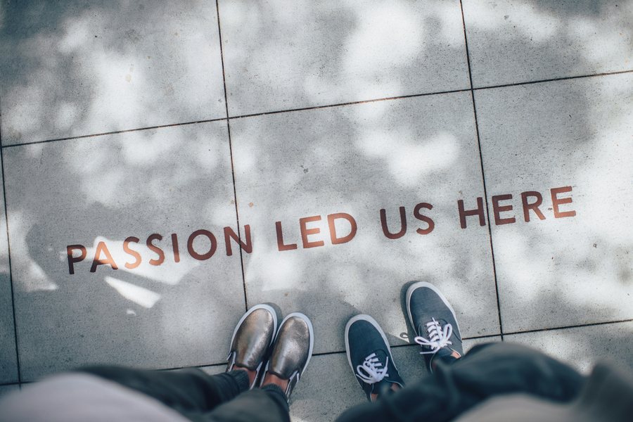 "Passion led us here" painted on the pavement, with two people standing in front of it