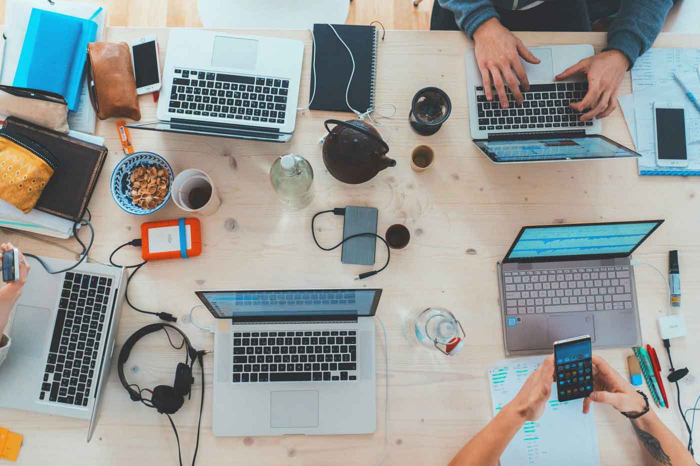 An overhead view of laptops and notebooks on a desk, working on digital resources